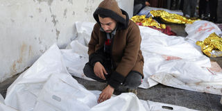 A person mourns near the bodies of Palestinians killed in Israeli strikes